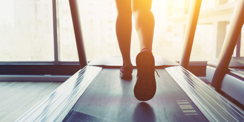 photo of woman's legs running on a treadmill as sun shines through window