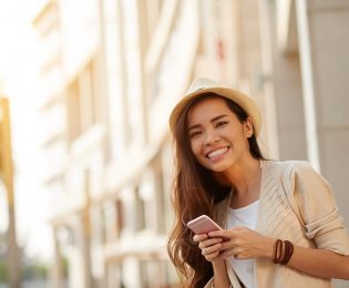 photo of girl in fedora smiling and holding a smart phone